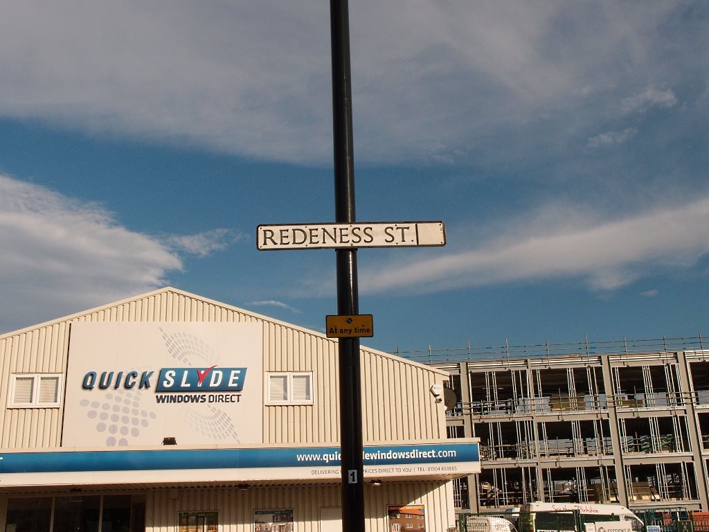 Street sign for Redeness St, with modern buildings behind